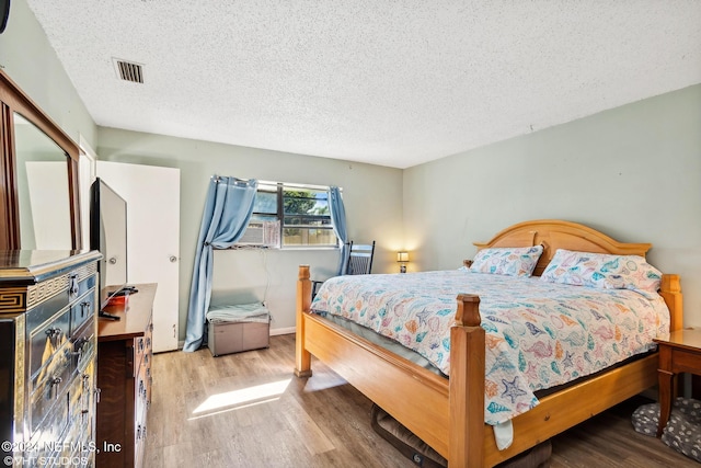 bedroom with hardwood / wood-style floors and a textured ceiling