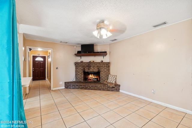 unfurnished living room with ceiling fan, a fireplace, light tile patterned flooring, and a textured ceiling