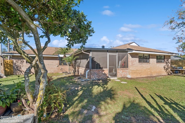 back of property featuring a sunroom and a lawn