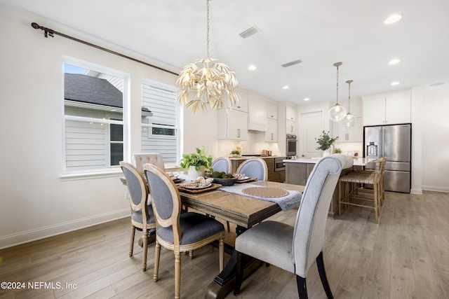 dining space with light wood-type flooring and an inviting chandelier