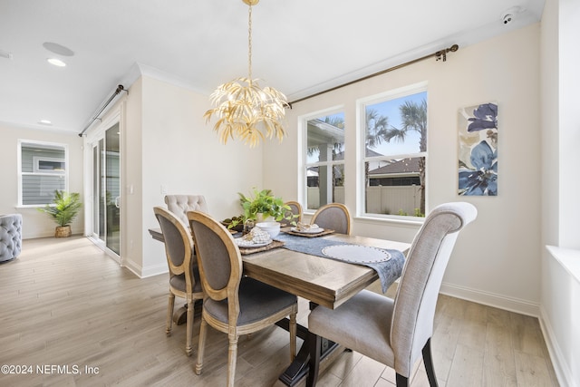 dining area featuring light wood-type flooring, ornamental molding, and an inviting chandelier