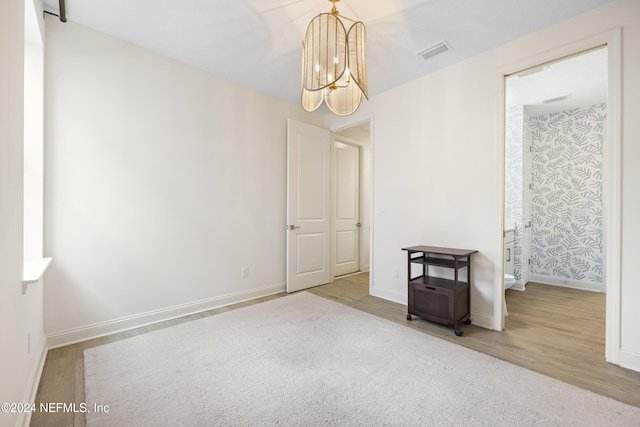 empty room with hardwood / wood-style floors and an inviting chandelier