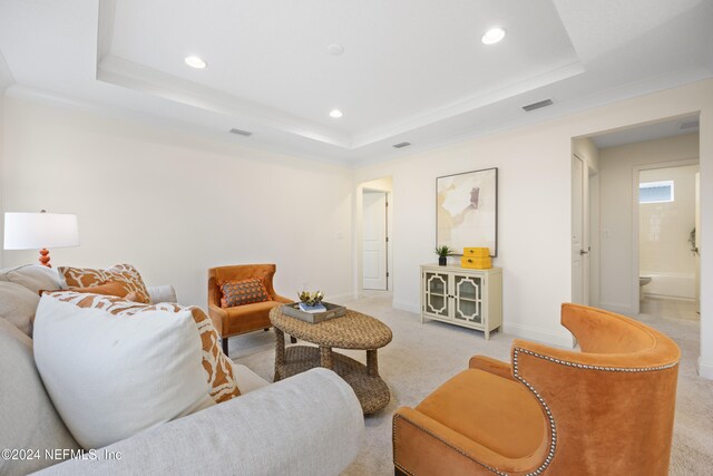 living room with light carpet, a raised ceiling, and ornamental molding