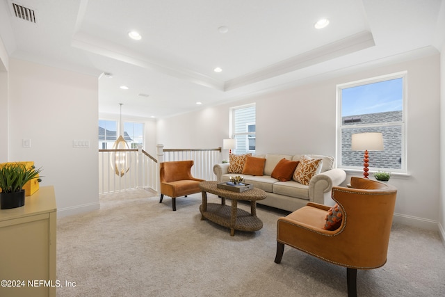 carpeted living room with a tray ceiling, crown molding, and a healthy amount of sunlight