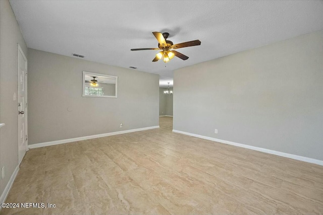 empty room featuring a textured ceiling and ceiling fan with notable chandelier