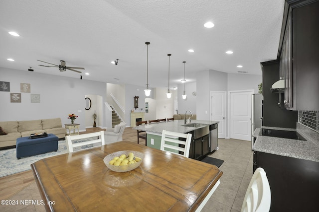 tiled dining space featuring a textured ceiling, ceiling fan, and sink