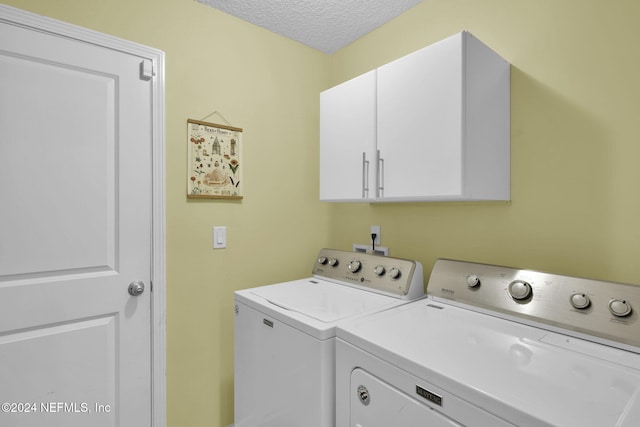 laundry area featuring washer and dryer, cabinets, and a textured ceiling