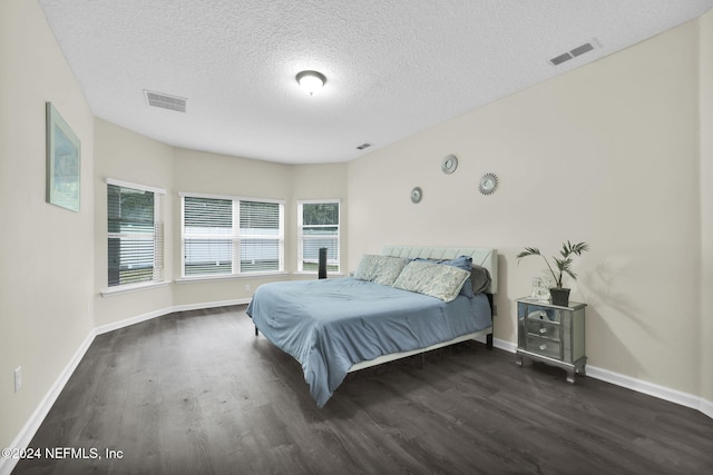 bedroom featuring a textured ceiling and dark hardwood / wood-style flooring