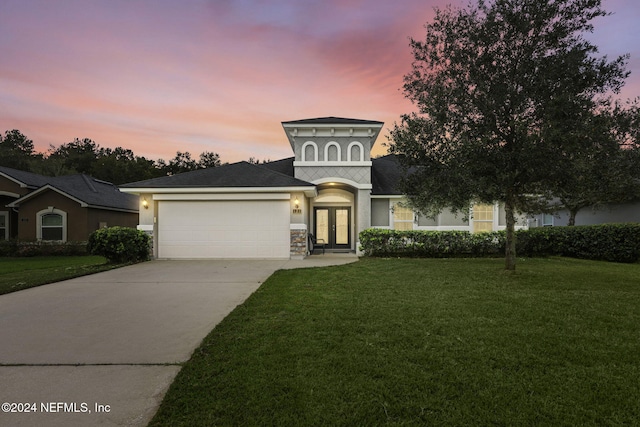 view of front of home with a yard, french doors, and a garage