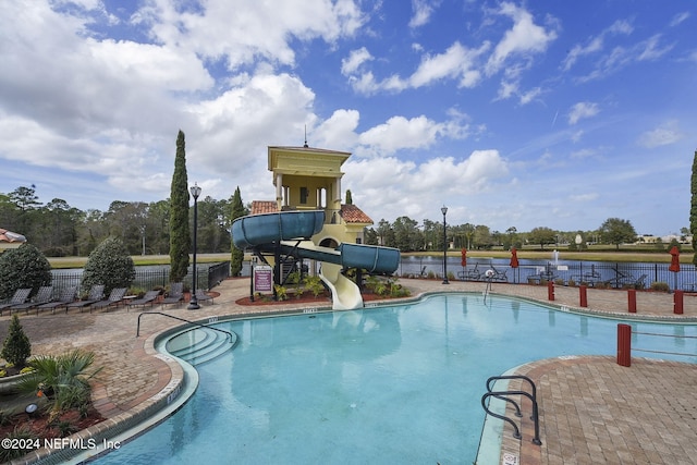 view of pool with a water view, a patio area, and a water slide