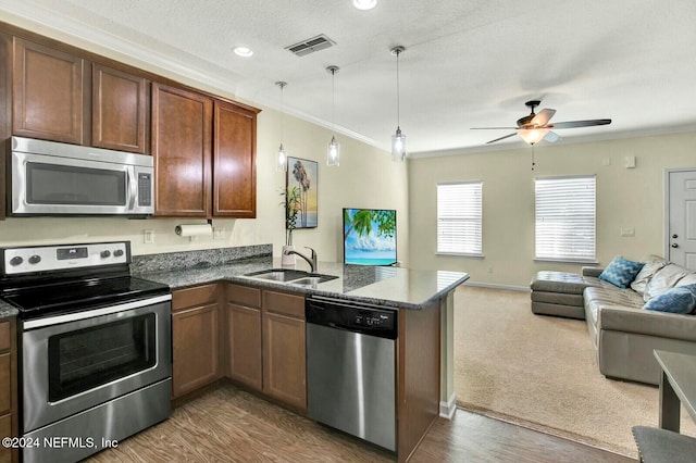 kitchen featuring sink, dark hardwood / wood-style floors, kitchen peninsula, decorative light fixtures, and appliances with stainless steel finishes