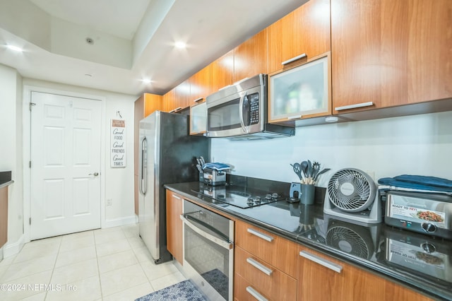 231 Riverside Dr Unit 1203-1, Daytona Beach, FL 32117 - kitchen featuring appliances with stainless steel finishes, brown cabinetry, light tile patterned floors, dark stone counters, and recessed lighting