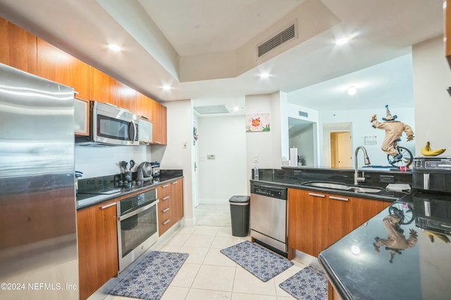 231 Riverside Dr Unit 1203-1, Daytona Beach, FL 32117 - kitchen featuring appliances with stainless steel finishes, brown cabinets, light tile patterned floors, modern cabinets, and a raised ceiling