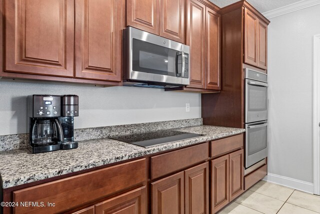 kitchen featuring crown molding, light stone counters, light tile patterned floors, and stainless steel appliances