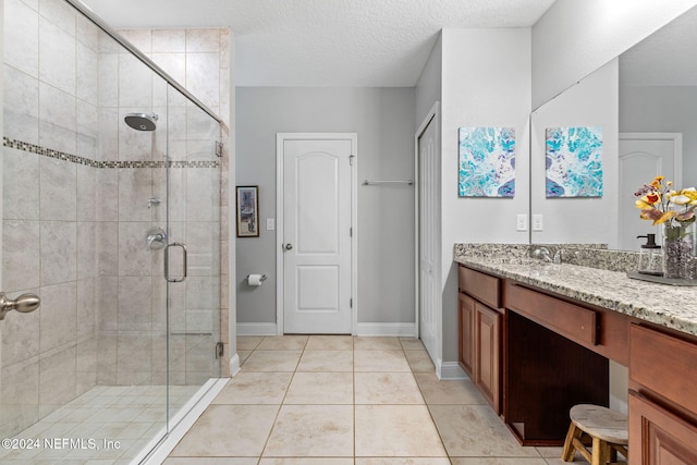 bathroom with tile patterned floors, vanity, walk in shower, and a textured ceiling