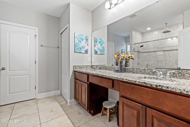 bathroom featuring tile patterned flooring, vanity, a textured ceiling, and a shower with shower door