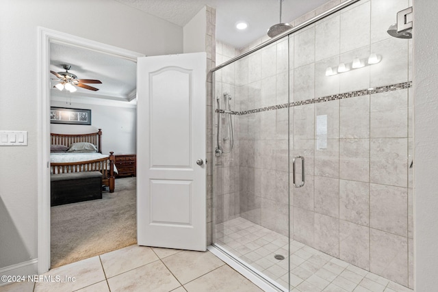 bathroom featuring ceiling fan, tile patterned flooring, a shower with door, and a textured ceiling