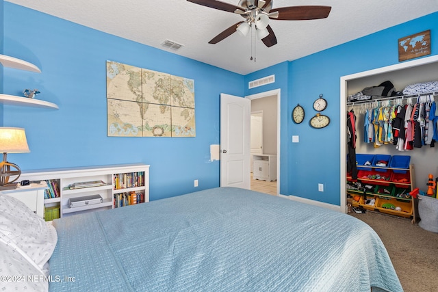 bedroom featuring ceiling fan, a closet, light colored carpet, and a textured ceiling