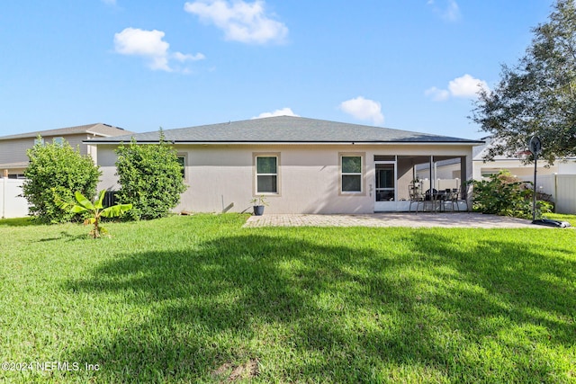 back of property with a lawn, a sunroom, and a patio