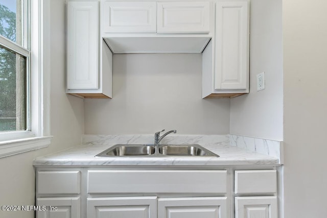 kitchen with sink, white cabinets, and light stone counters