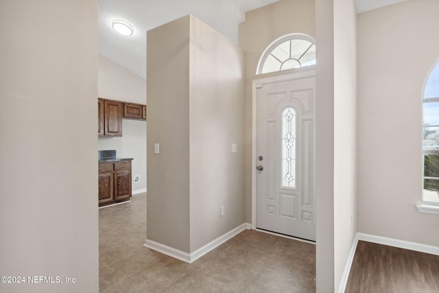 foyer featuring a textured ceiling and vaulted ceiling