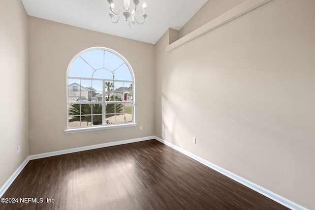 unfurnished room with a textured ceiling, dark hardwood / wood-style flooring, a chandelier, and vaulted ceiling