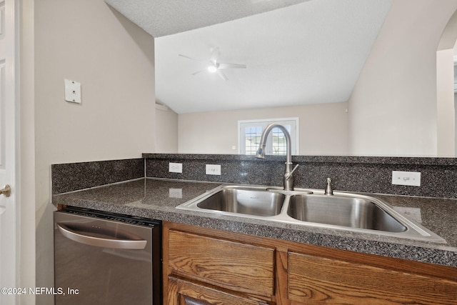 kitchen featuring a textured ceiling, dishwasher, sink, and vaulted ceiling