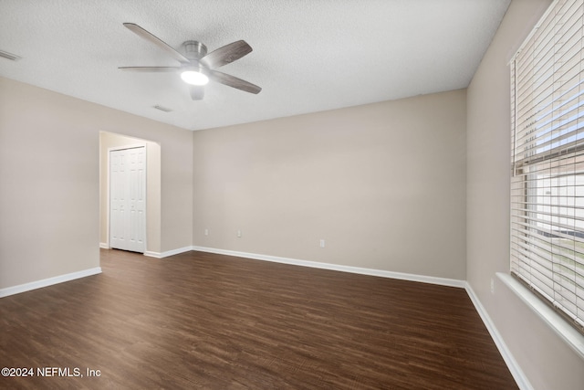 unfurnished room featuring a textured ceiling, ceiling fan, and dark wood-type flooring