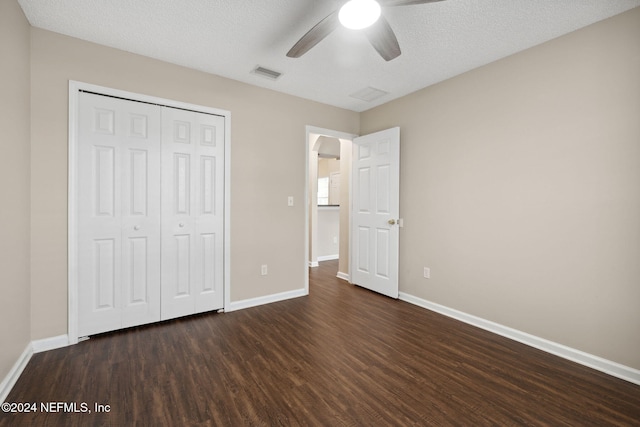 unfurnished bedroom featuring a textured ceiling, a closet, ceiling fan, and dark wood-type flooring