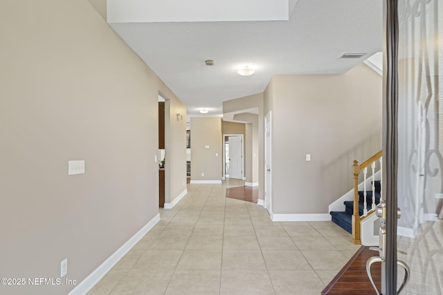 hallway with a textured ceiling and light tile patterned floors