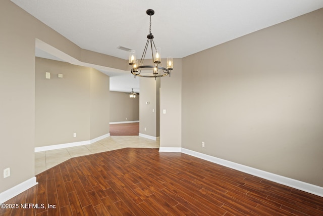 unfurnished room with ceiling fan with notable chandelier