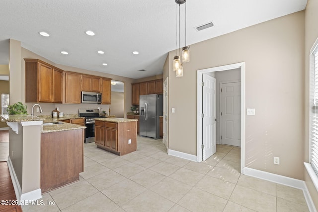 kitchen with decorative light fixtures, kitchen peninsula, sink, appliances with stainless steel finishes, and light stone countertops