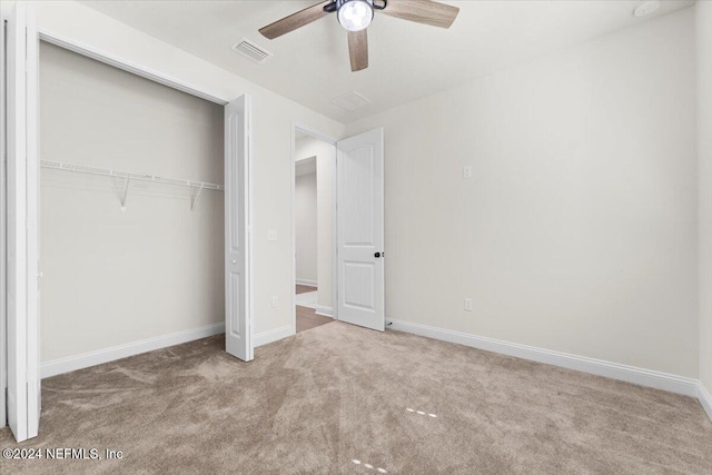 unfurnished bedroom featuring a closet, light colored carpet, and ceiling fan