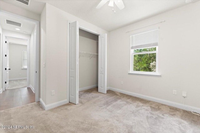 unfurnished bedroom featuring light carpet, a closet, and ceiling fan