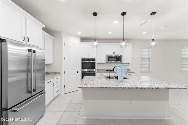 kitchen with white cabinets, a kitchen island with sink, and appliances with stainless steel finishes