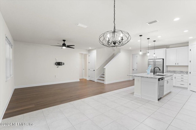 kitchen with white cabinets, light hardwood / wood-style floors, an island with sink, and hanging light fixtures