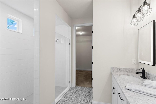 bathroom with tiled shower and vanity