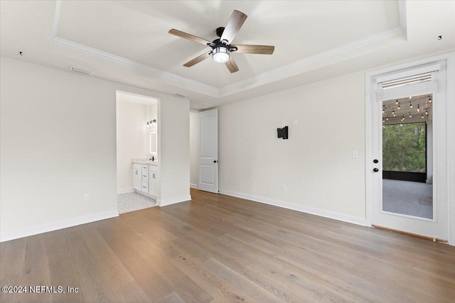 spare room featuring ornamental molding, a tray ceiling, ceiling fan, and light hardwood / wood-style floors