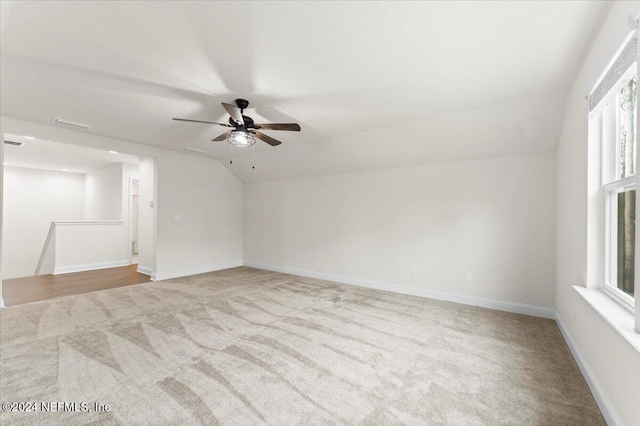 unfurnished room with light colored carpet, vaulted ceiling, and ceiling fan