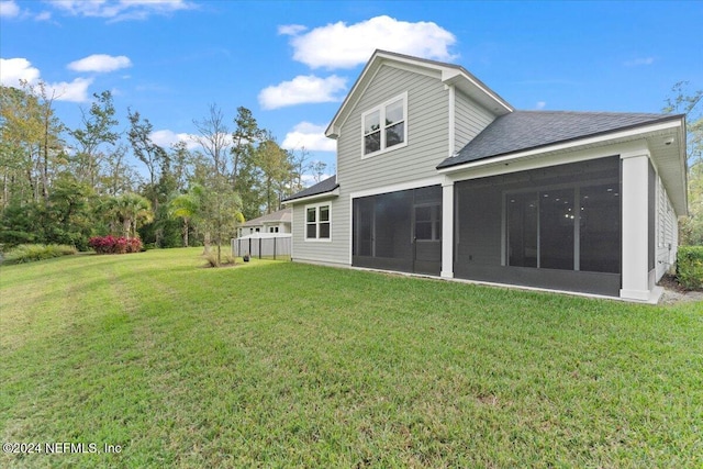 rear view of property featuring a sunroom and a yard