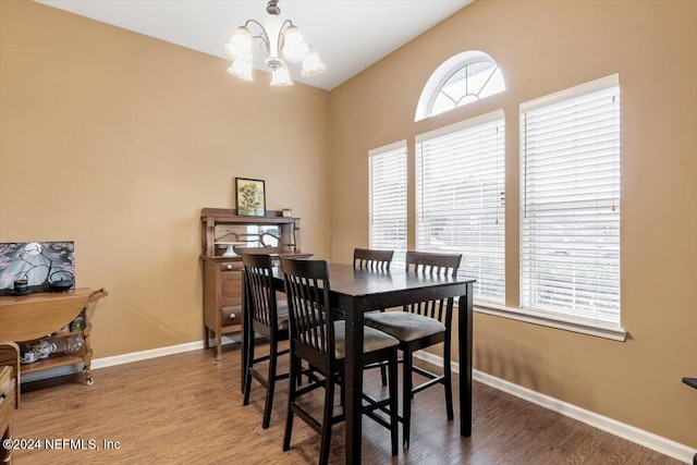 dining room featuring wood-type flooring, vaulted ceiling, and an inviting chandelier