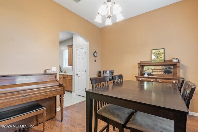 dining area with a chandelier, light hardwood / wood-style floors, and vaulted ceiling