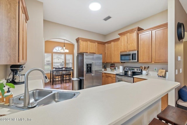 kitchen with kitchen peninsula, appliances with stainless steel finishes, sink, a notable chandelier, and a breakfast bar area