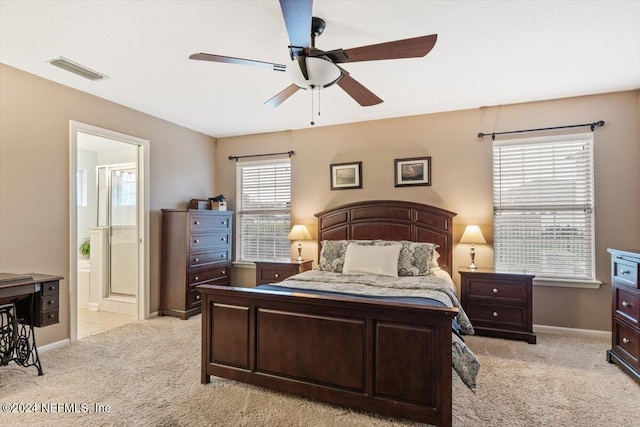 carpeted bedroom with ensuite bath and ceiling fan