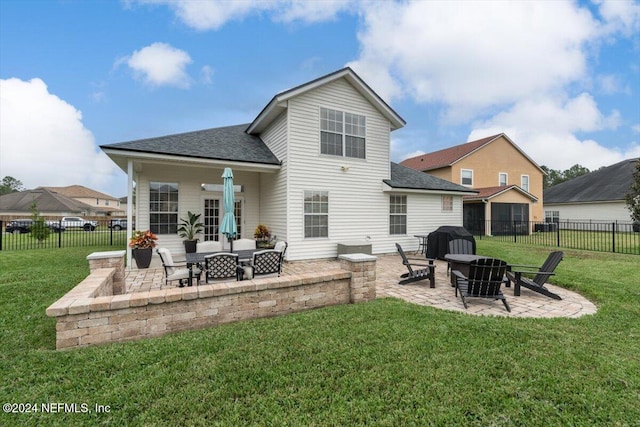 rear view of house featuring a patio area, a yard, and a fire pit