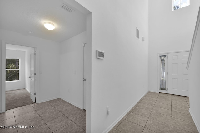 corridor featuring a wealth of natural light, light tile patterned floors, and a textured ceiling