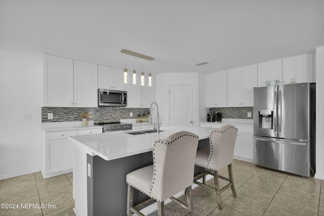 kitchen featuring appliances with stainless steel finishes, a breakfast bar, sink, hanging light fixtures, and an island with sink