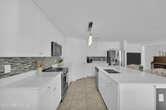 kitchen featuring tasteful backsplash, stainless steel appliances, a kitchen island with sink, sink, and white cabinets