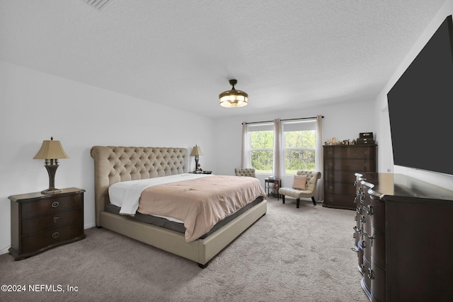 bedroom with light carpet and a textured ceiling