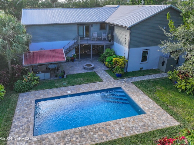 back of house featuring a lawn, a patio area, and an outdoor fire pit